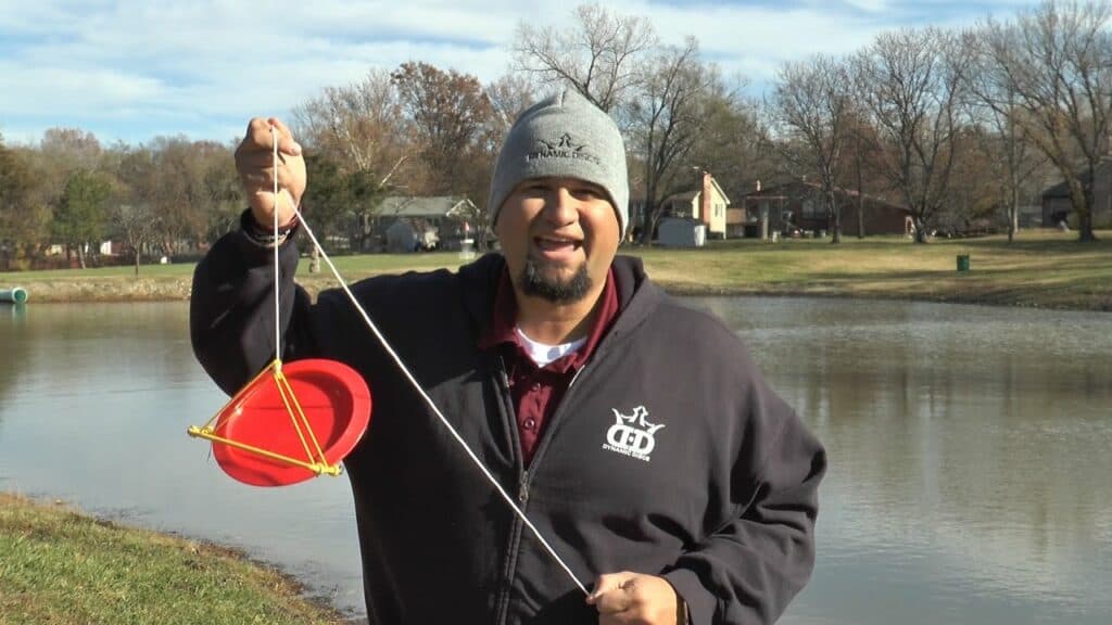 A disc golfer using a retriever to get a disc out of water.