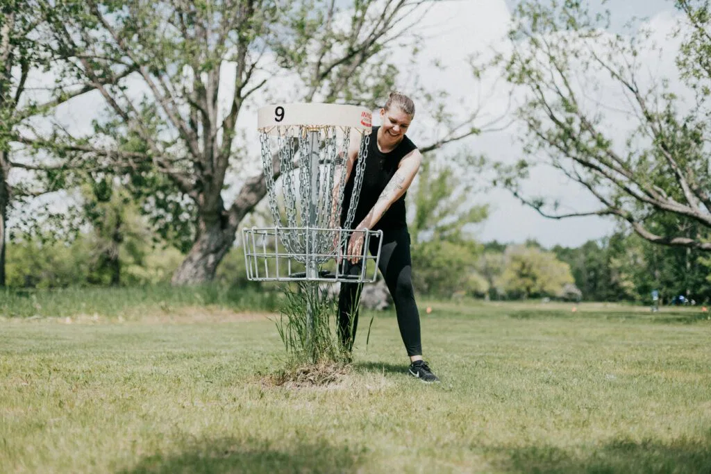 disc golfer taking her disc out of the basket.