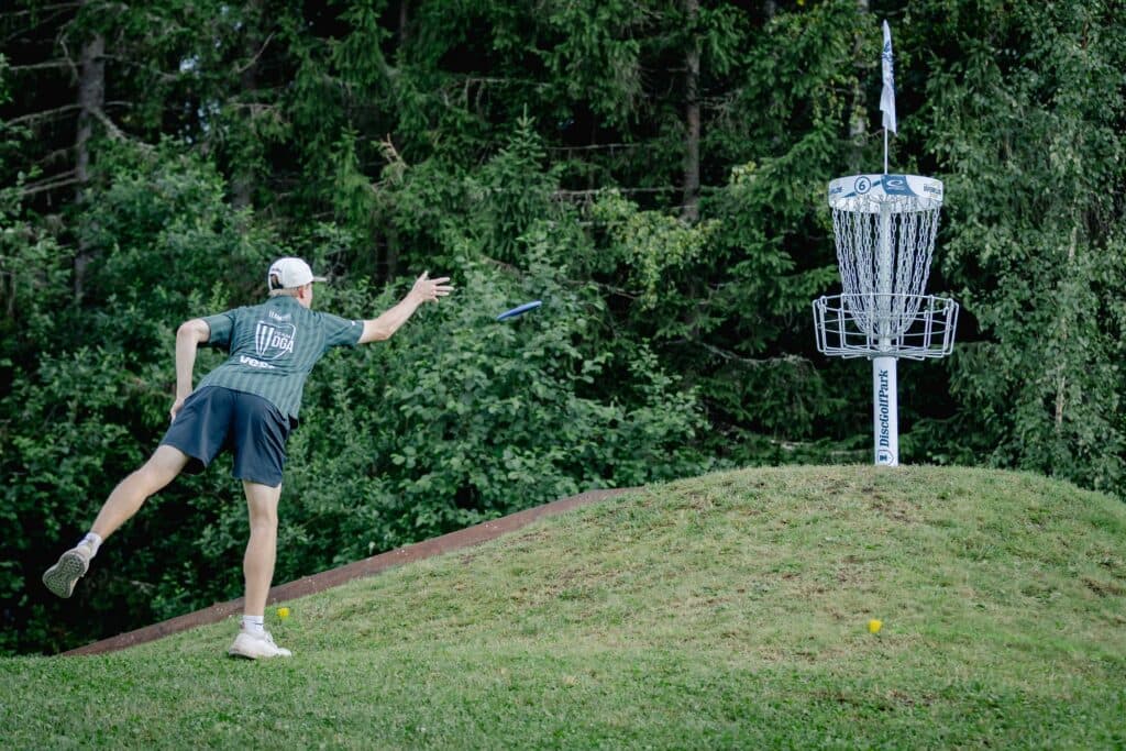 A pro disc golfer putting into a basket
