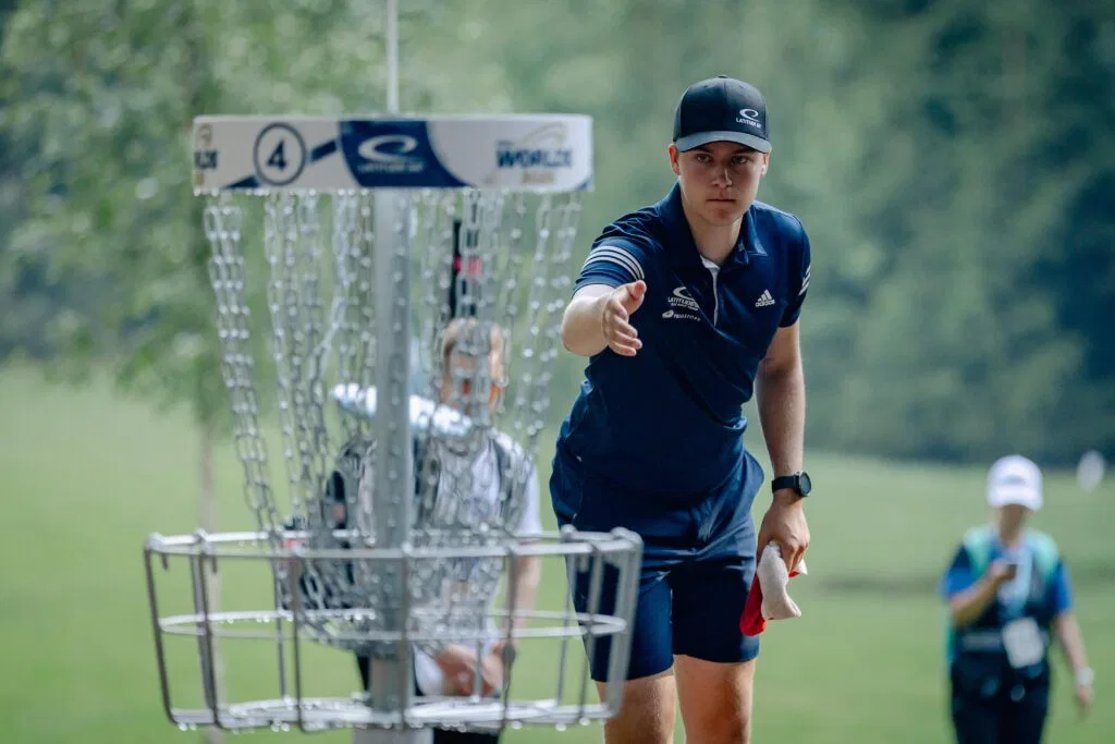 A pro disc golfer putting into a basket