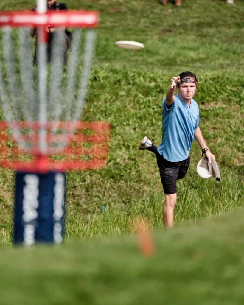 A professional disc golfer putting into a basket